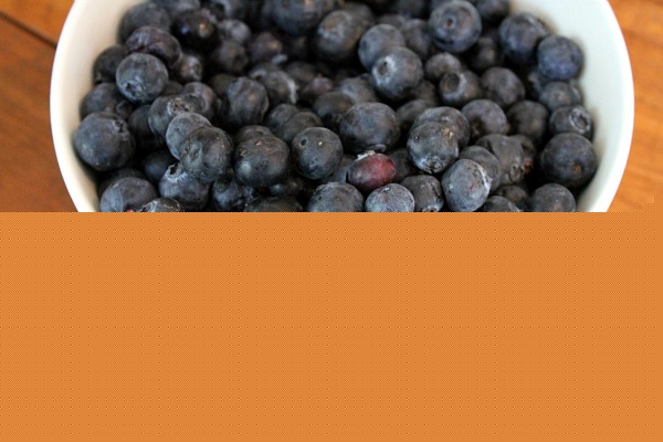 Blueberries in a white dish sitting on a wooden surface