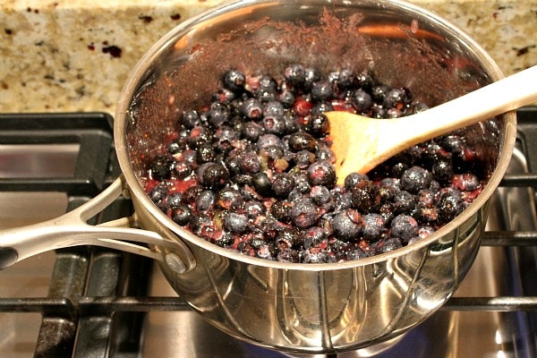 Blueberries in a pot on the stove with a wooden spoon. Ready to be cooked into jam.