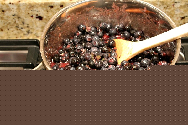 Blueberries in a pot on the stove with a wooden spoon. Ready to be cooked into jam.