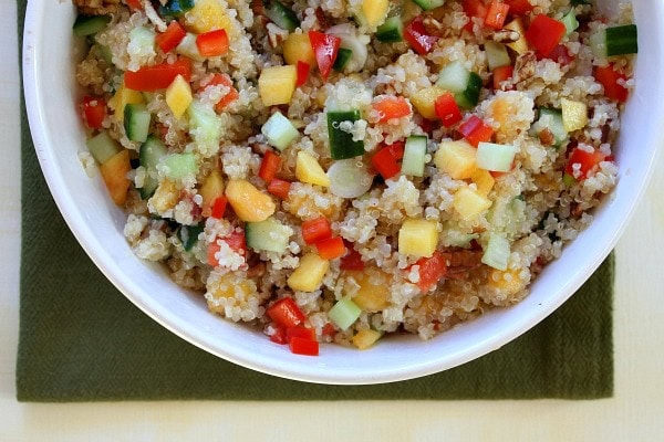 Overhead shot of half a bowl of Peach and Pecan Quinoa Salad in a white bowl set on a green napkin