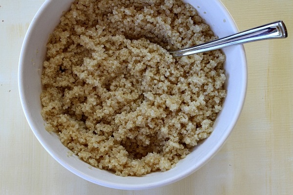 cooked Quinoa in a white bowl with a spoon