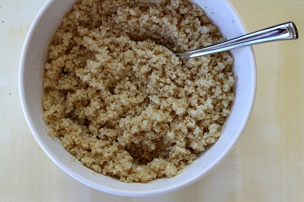 Peach and Pecan Quinoa Salad recipe from RecipeGirl.com #peach #pecan #quinoa #salad #recipe #RecipeGirl cooked Quinoa in a white bowl with a spoon