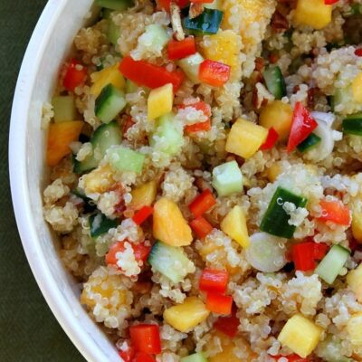 overhead shot of half of a peach and pecan quinoa salad in a white bowl