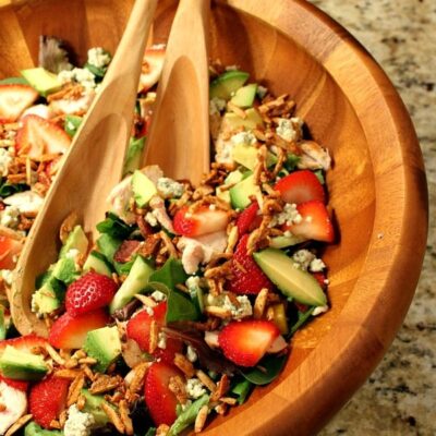 strawberry chicken salad in a big wooden bowl with wooden serving spoons