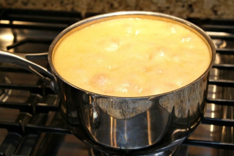 peach freezer jam ingredients boiling in a saucepan on the stove