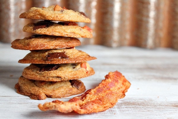 stack of 6 Bourbon Bacon Chocolate Chunk Cookies with a slice of bacon sitting alongside