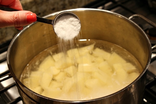 Adding salt to potatoes in water in pan