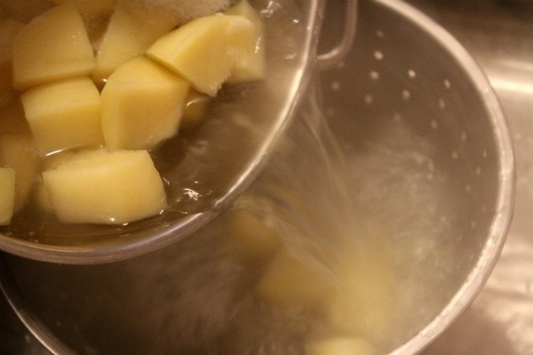 Perfect Mashed Potatoes recipe from RecipeGirl.com #perfect #mashed #potatoes #recipe #RecipeGirl pouring potatoes into a strainer