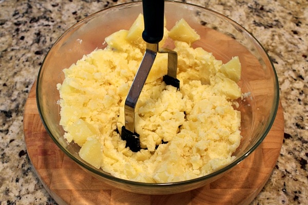 Perfect Mashed Potatoes recipe from RecipeGirl.com #perfect #mashed #potatoes #recipe #RecipeGirl Mashing potatoes in a bowl