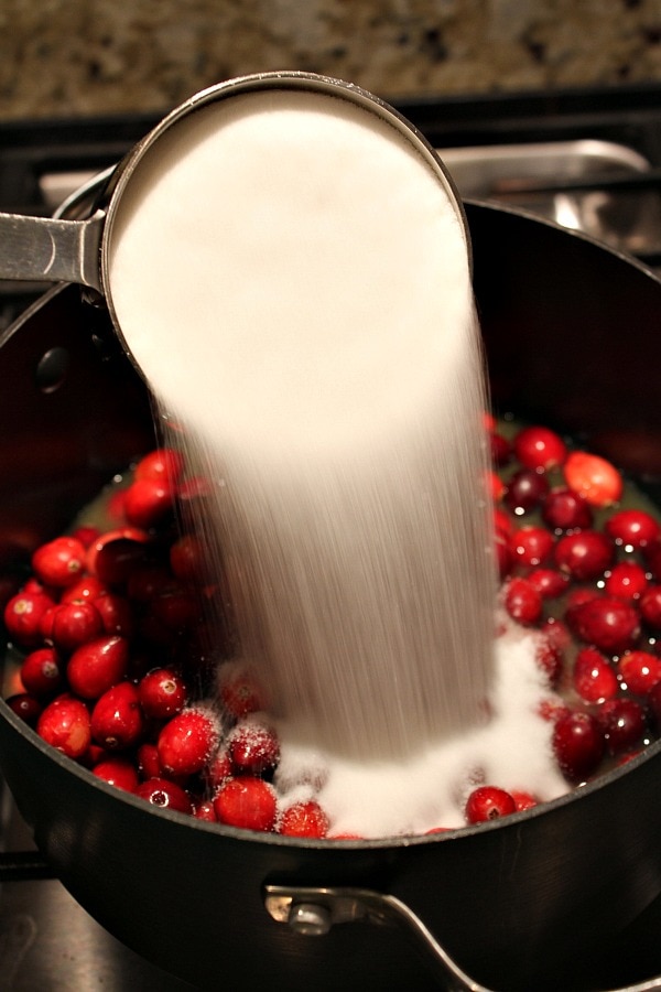 Pouring sugar into pan with cranberries