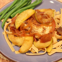 chicken with apples over pasta on plate