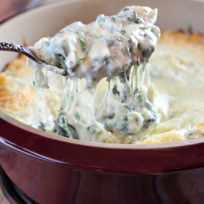 lightened up spinach artichoke dip spooning out of dish