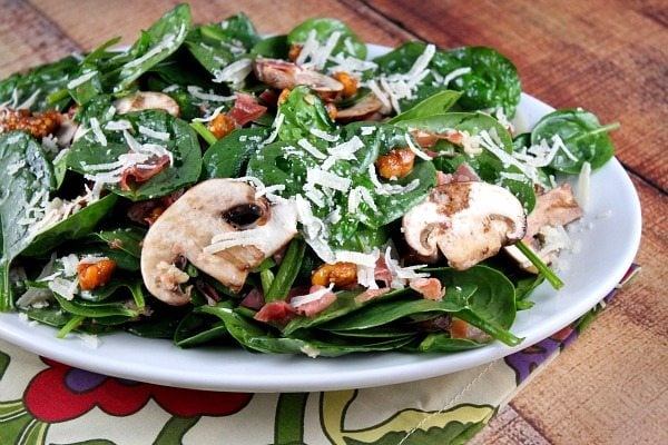 Spinach Salad with Hot Prosciutto Dressing recipe from RecipeGirl.com #spinach #salad #hot #prosciutto #dressing #recipe #RecipeGirl Spinach Salad with Hot Prosciutto Dressing on a white platter