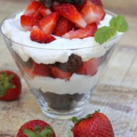brownie strawberry shortcake in a clear glass with fresh strawberries scattered around