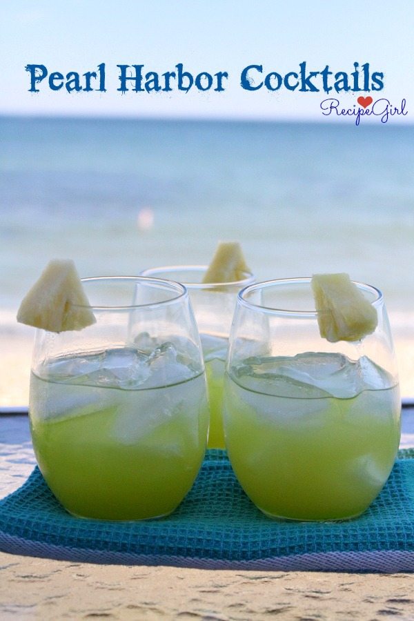 two Pearl Harbor Cocktails sitting side by side on a blue towel with the ocean in the background