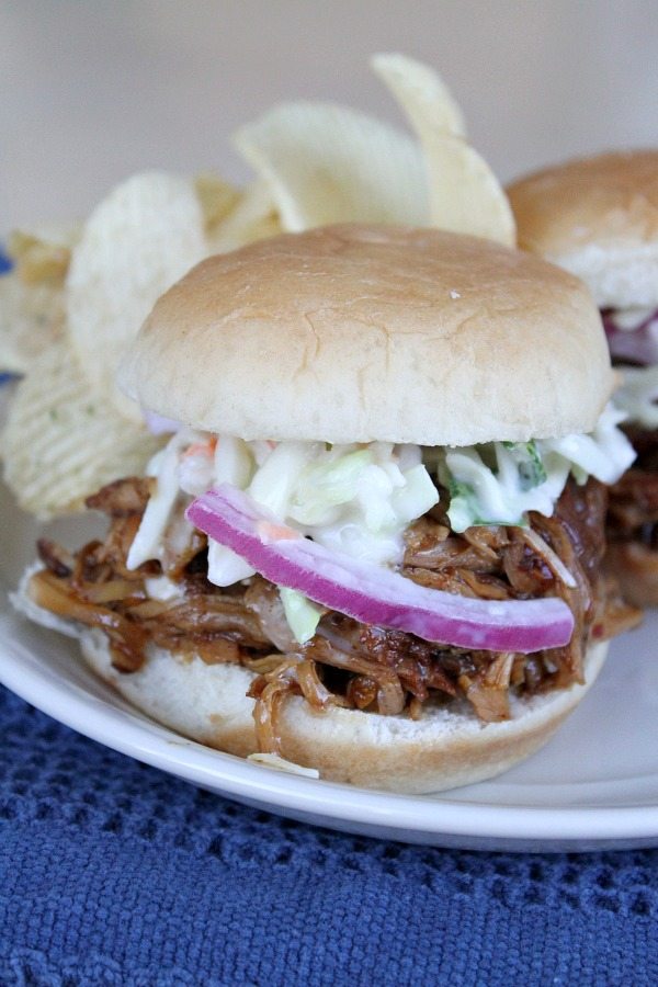 Slow Cooker Pulled Pork Slider on a white plate with chips, set on a blue napkin