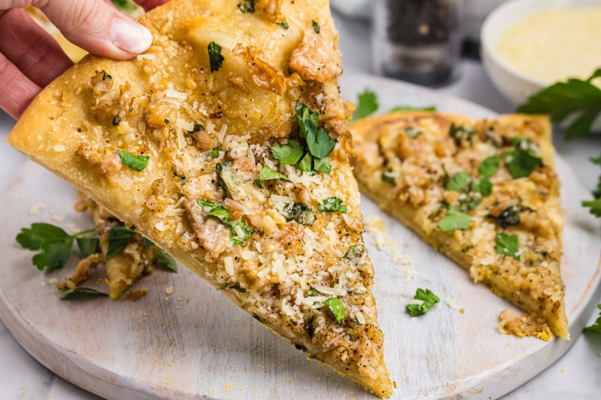 hand picking up slice of white clam pizza