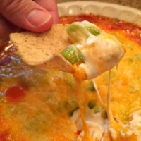 hand holding chip dipped into buffalo chicken dip