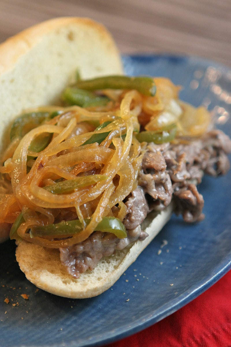 Philly Cheese Steak Sandwiches recipe from RecipeGirl.com #philly #cheese #steak #cheesesteak #sandwiches #recipe #RecipeGirl Philly Cheese Steak Sandwiches with Peppers and Onions on a blue plate