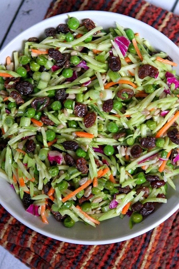 overhead shot of a bowl of broccoli slaw set on top of a burgundy striped cloth napkin