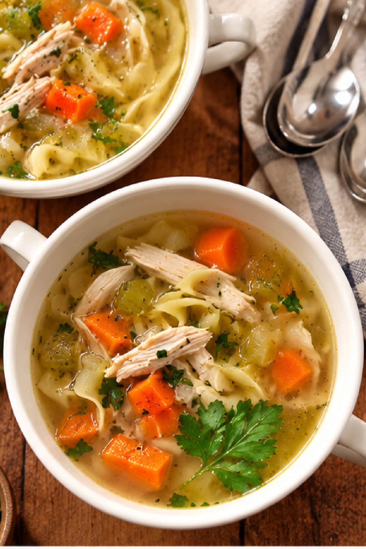 Save this Classic Chicken Soup recipe for chilly days! A whole chicken is slowly simmered in flavorful broth with carrots, celery, onion, parsnip and fresh herbs. Keep it simple or add noodles to turn it into homemade chicken noodle soup. overhead shot classic chicken soup in bowls