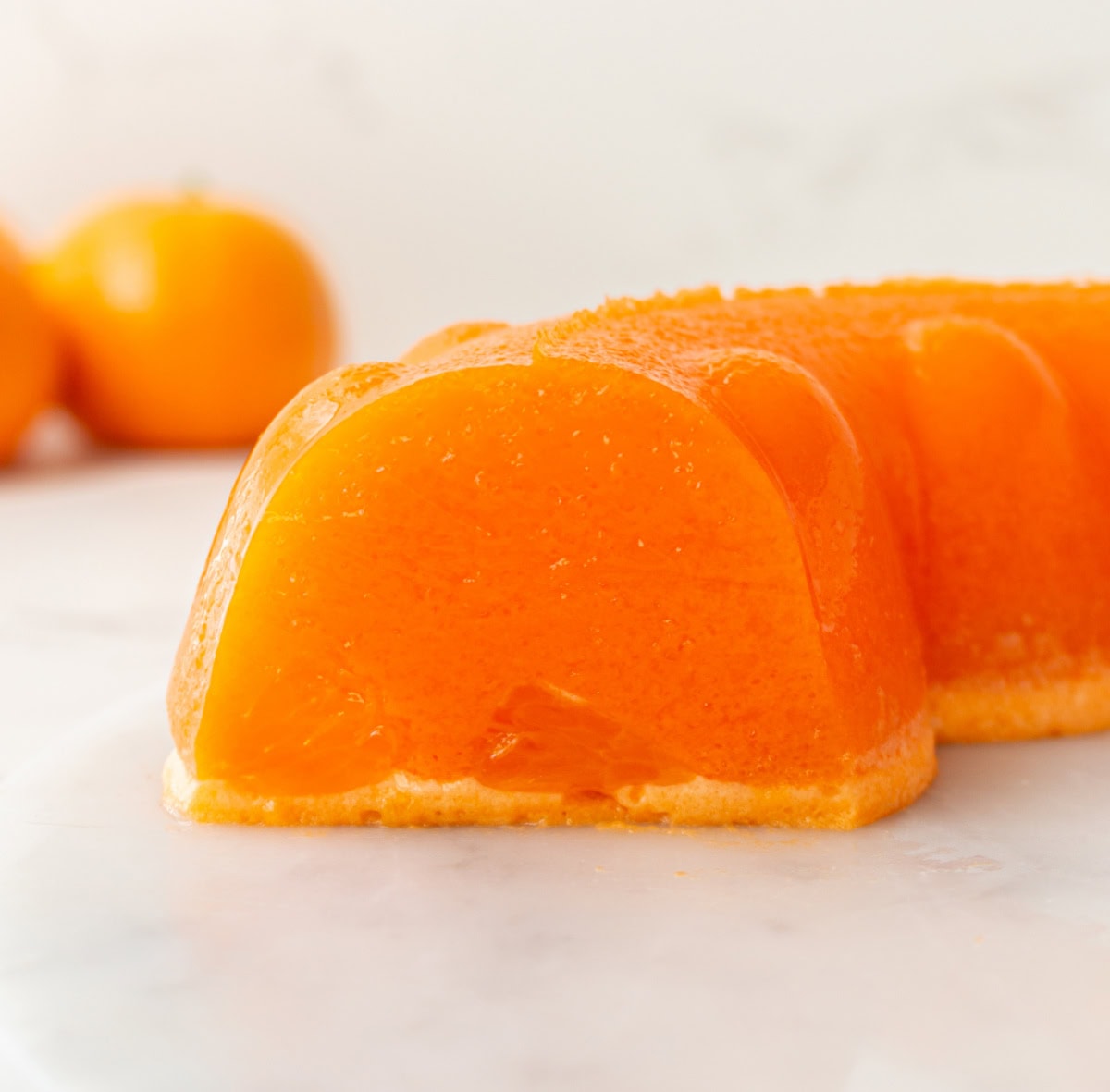 Cool, creamy, and perfectly nostalgic — this Orange Sherbet Jello Salad is made with orange Jell-O, sherbet, and mandarin oranges. The perfect citrusy dessert for holidays, brunches, and family gatherings! orange sherbet jello salad sliced to see the inside