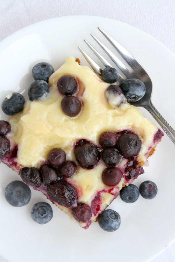 slice of blueberry gooey butter cake on a white plate with a fork