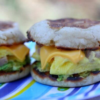 two camping breakfast sandwiches sitting side by side on a blue striped tablecloth