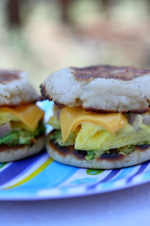 two camping breakfast sandwiches sitting side by side on a blue striped tablecloth