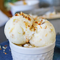 Coconut Frozen Yogurt scooped into a white serving dish sitting on a blue tablecloth