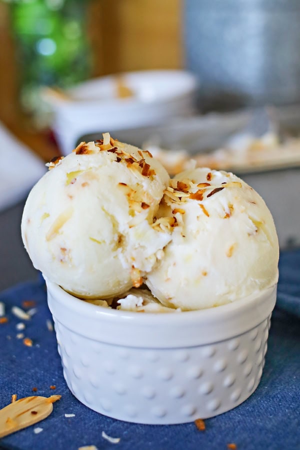 Coconut Frozen Yogurt scooped into a white serving dish sitting on a blue tablecloth