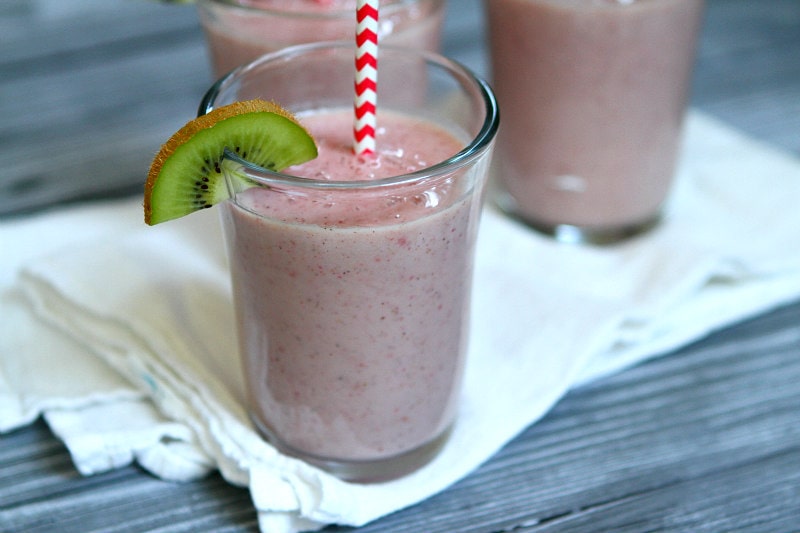 Kiwi Strawberry Smoothies in glasses garnished with a kiwi wedge and red/white straws