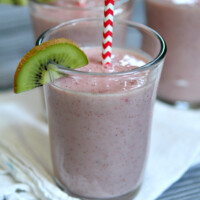 Kiwi Strawberry Smoothies in glasses garnished with a kiwi wedge and red/white straws