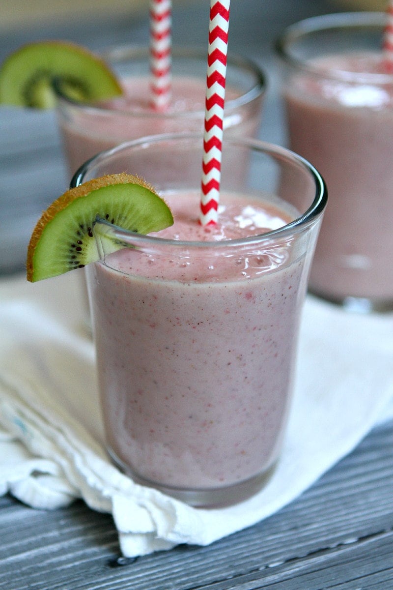 Kiwi Strawberry Smoothies in glasses garnished with a kiwi wedge and red/white straws