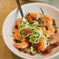 white bowl with fork of alfredo zoodles and shrimp