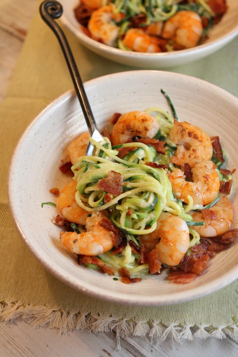 white bowl with fork of alfredo zoodles and shrimp