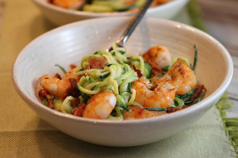 white bowl with fork of alfredo zoodles and shrimp