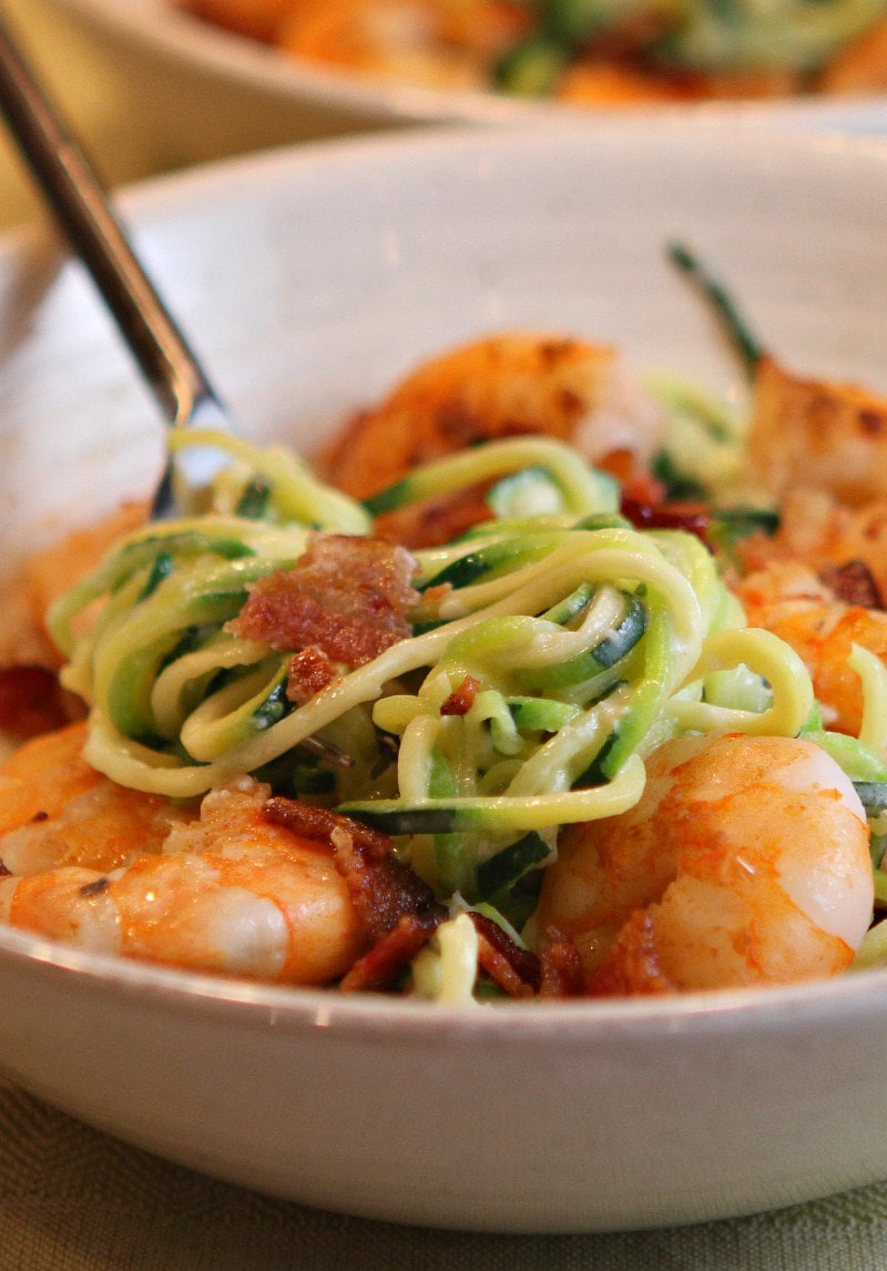 white bowl with fork of alfredo zoodles and shrimp