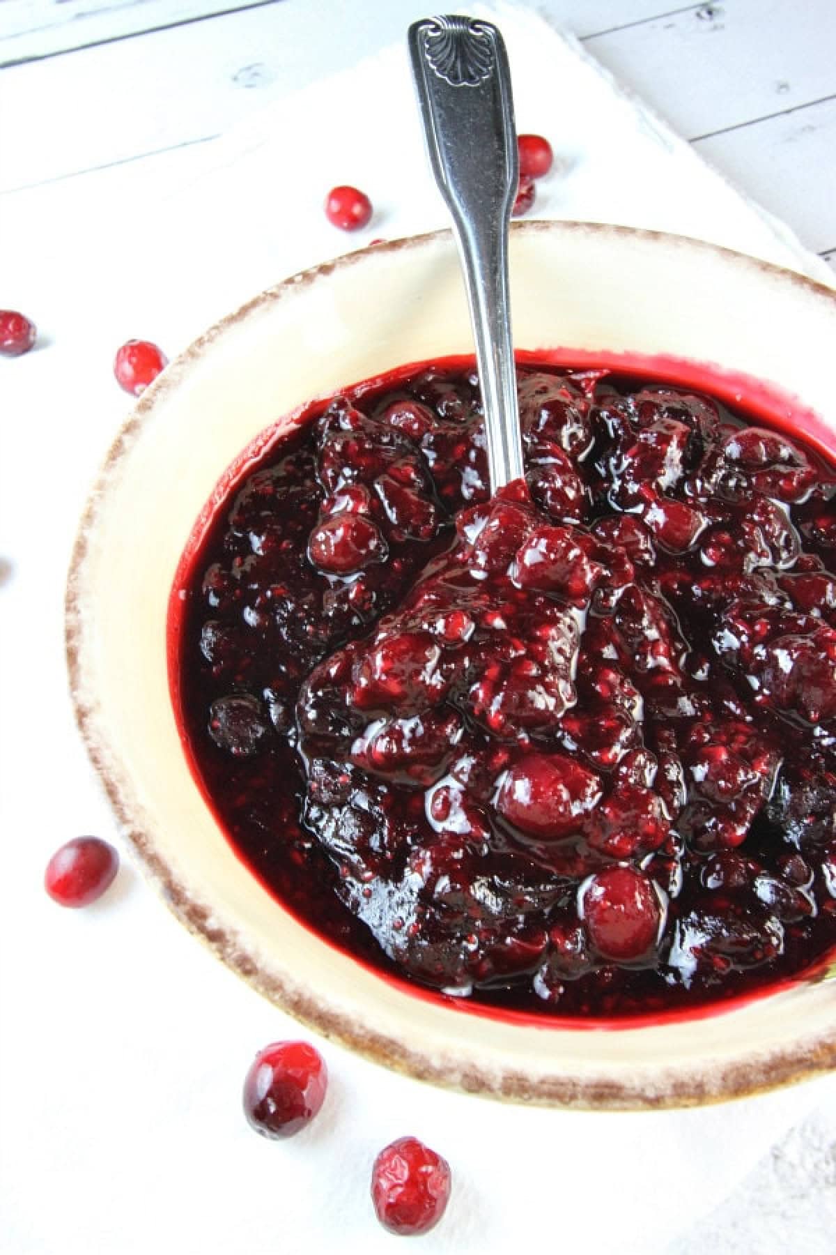 Sweet, tart, and full of flavor — this Sherry Triple Berry Cranberry Sauce combines cranberries, blueberries, and raspberries with a splash of sherry for the ultimate holiday side. sherry triple berry cranberry sauce in bowl with spoon