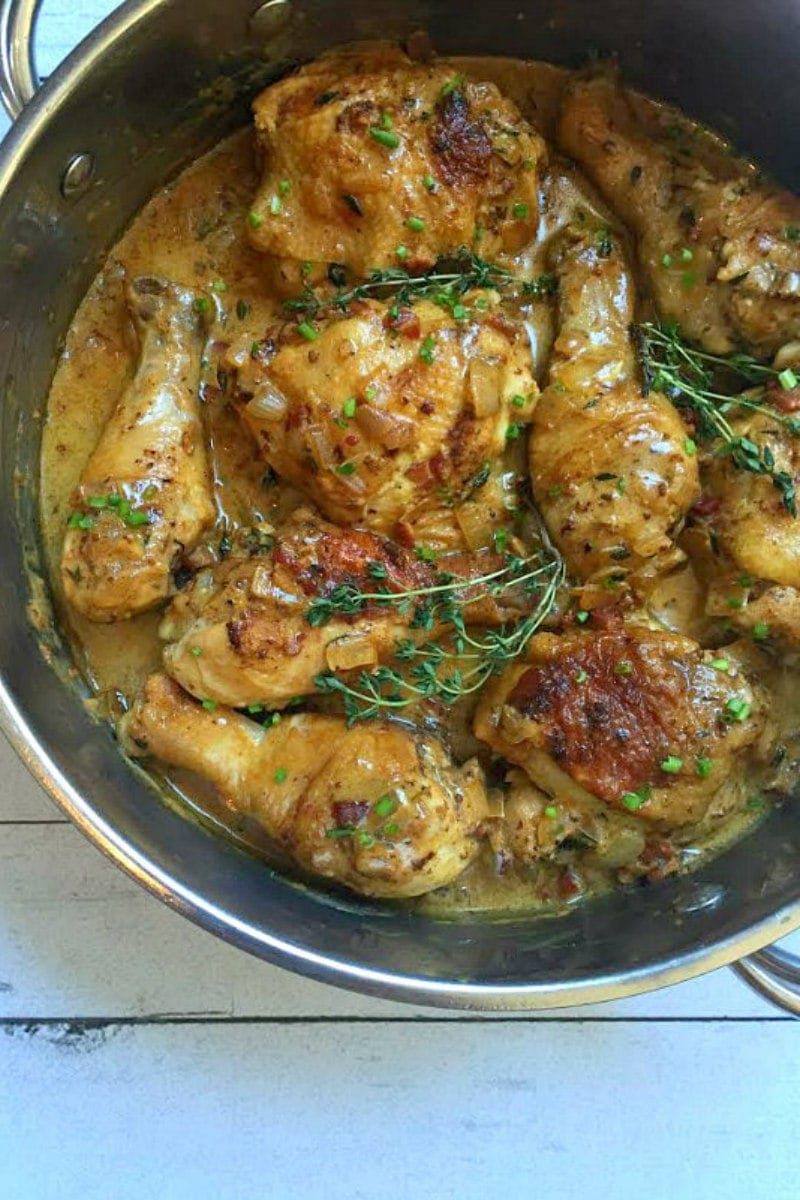 chicken pieces cooking in pan with sauce and fresh thyme