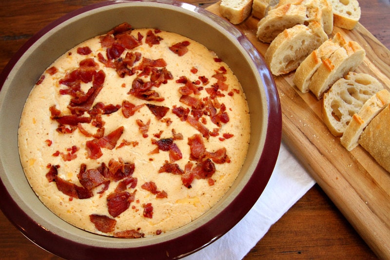 Beer and Bacon Dip in a bowl with sliced baguette on the side