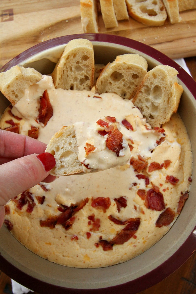 Baguette dipped in Beer and Bacon Dip on a slice of baguette 