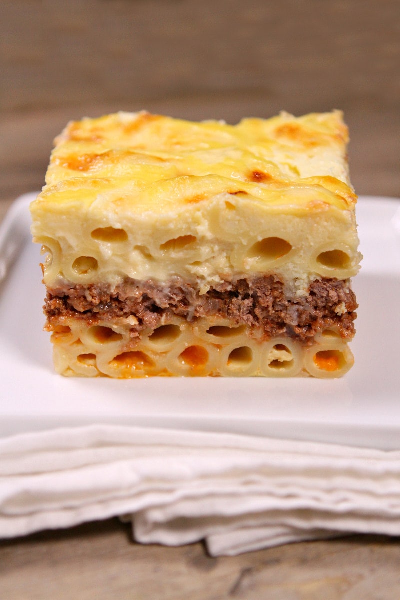 slice of pastitsio sitting on a white plate on a white napkin