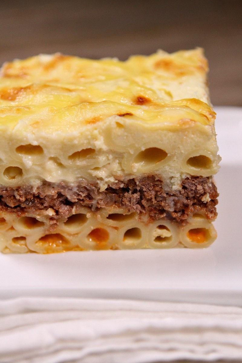 slice of pastitsio sitting on a white plate on a white napkin