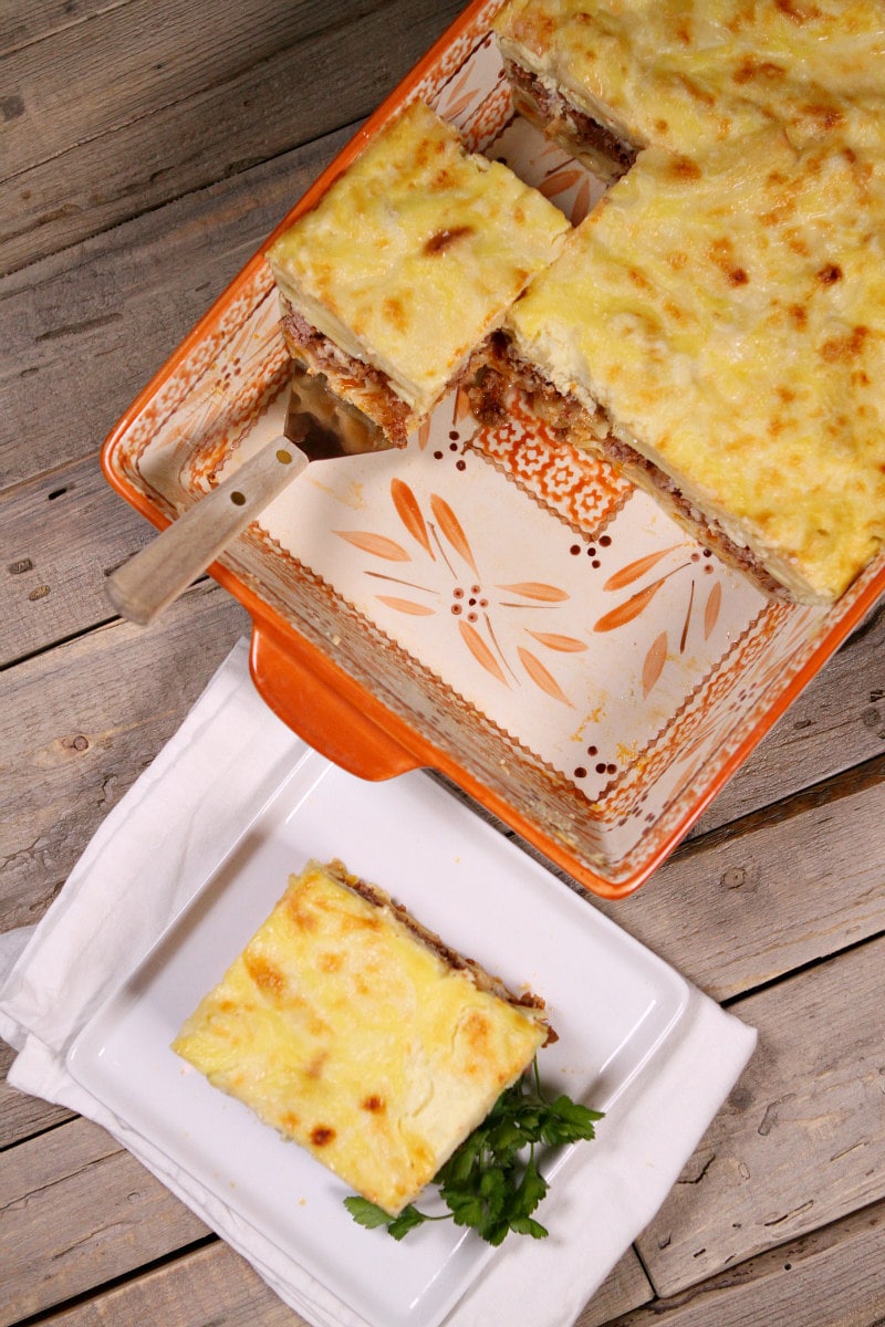 overhead shot of pastitsio in a casserole dish with spatula taking a slice out