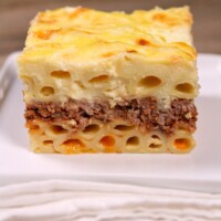 Slice of Pastitsio on a white plate with a white napkin