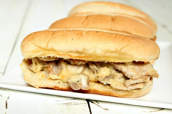 pork and melted cheese hoagies on a white serving platter