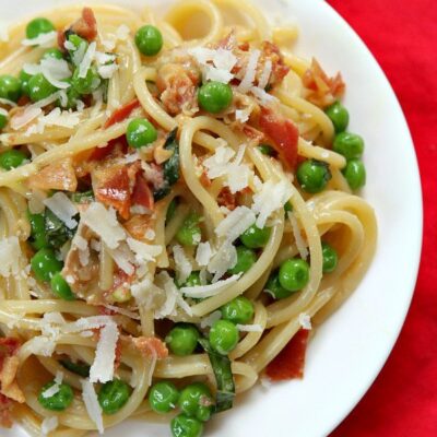 overhead shot of spaghetti carbonara on a white plate set on a red napkin