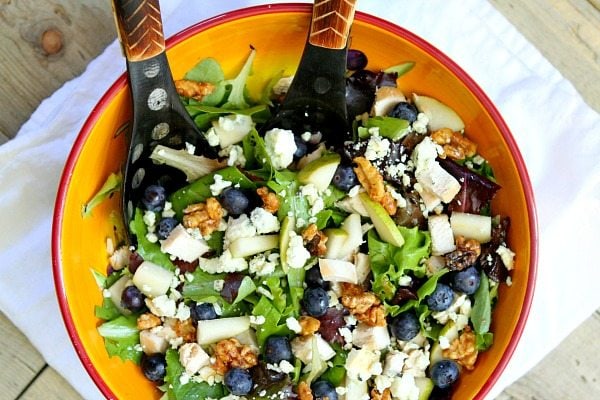 Blueberry, Blue Cheese and Glazed Walnut Salad in a yellow salad bowl with salad servers
