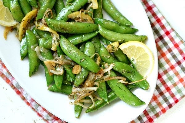 Overhead shot of Lemony Stir Fried Sugar Snap Peas on a white plate set on a checked napkin